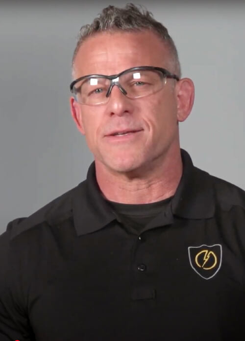 A headshot of a man in a black shirt wearing safety glasses