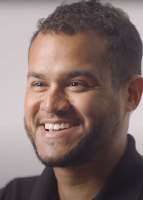 A headshot of a man in a black collared shirt